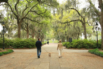 A couple walking their dog through one of Savannah's many squares.