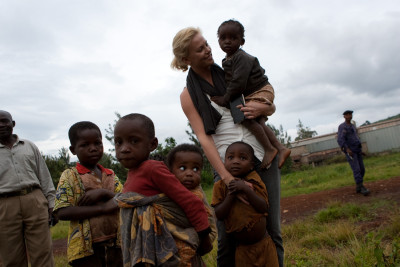 Actor Ms Chalize Theron, UN Ambassador for Peace, visits Panzi Hospital (which specializes in sexual violence against women) in Bukavu, South Kivu, DRC. While visiting the location for upcoming construction site of "City of Joy" (a transit centre for women-victims of sexual violence), Ms Theron greets local children. Background: Congolese Police Officer ensuring security during Ms Theron's visit.